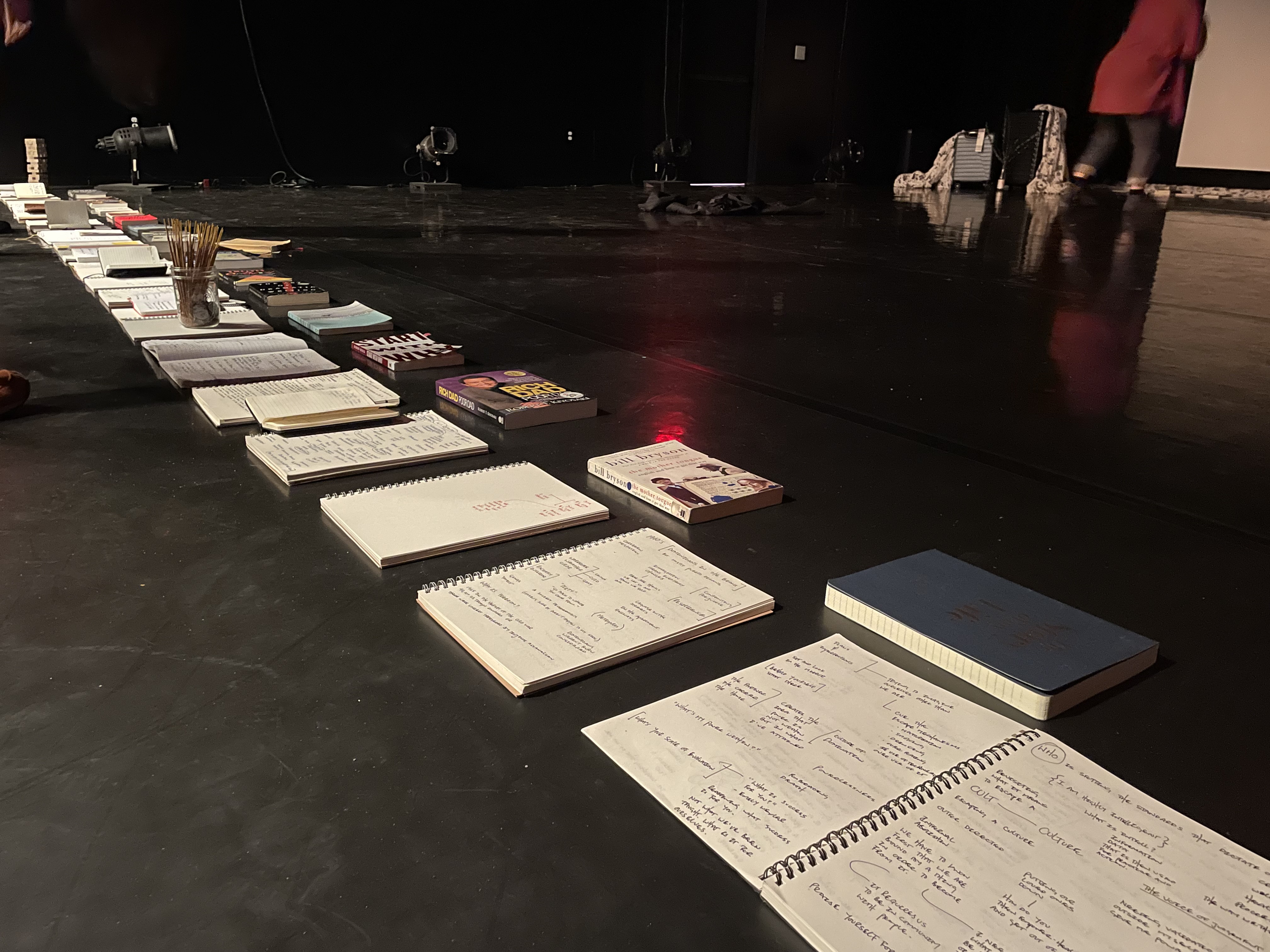 the black box theater lined with notebooks along the front end of the stage